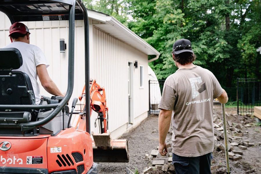 Crew walking onto a job site with a mini excavator