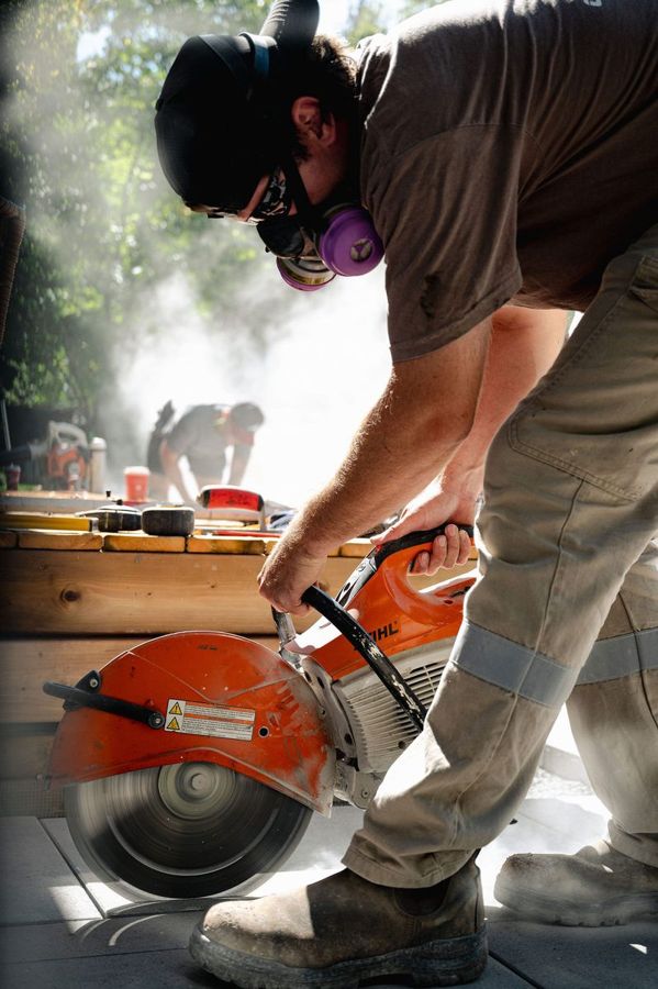 Crew member cutting a paver with a cut-off saw